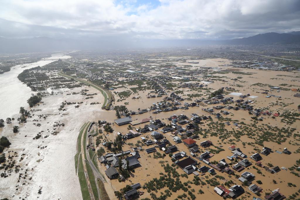 台風１９号　千曲川（左）の決壊現場。濁流が長野市側の住宅地（右）を襲った